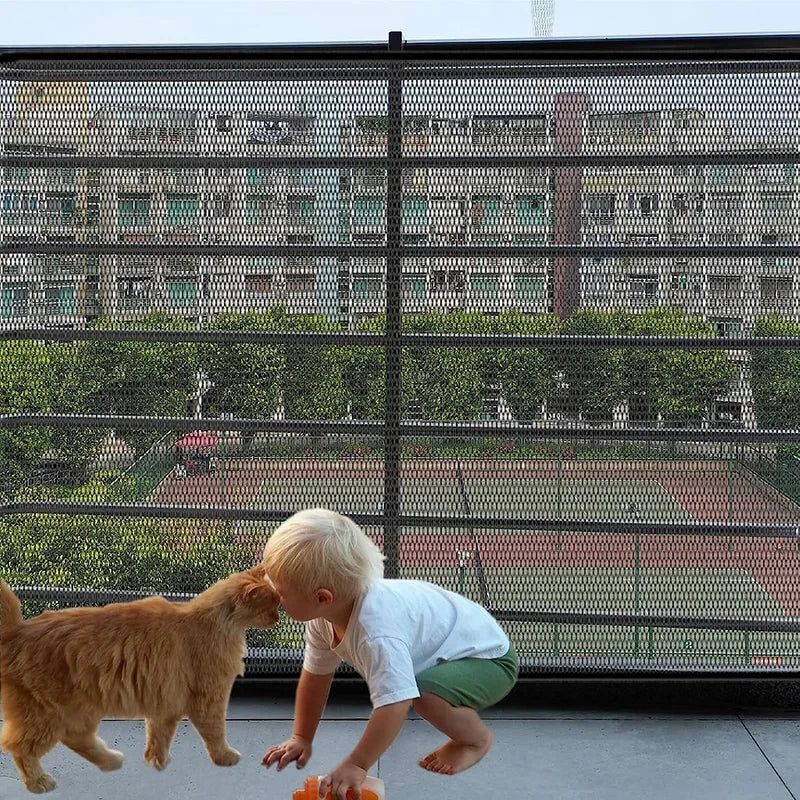 A cat and toddler playing in front of a mesh safety gate.