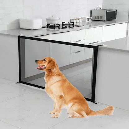 A brown dog sitting in front of a mesh safety gate mounted to prevent access to a kitchen.