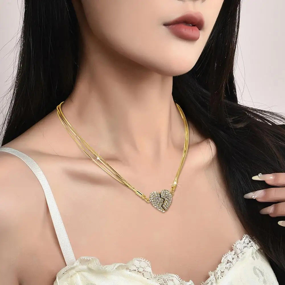 A woman wearing a gold chain with a broken heart rhinestone pendant, and neckline showing.