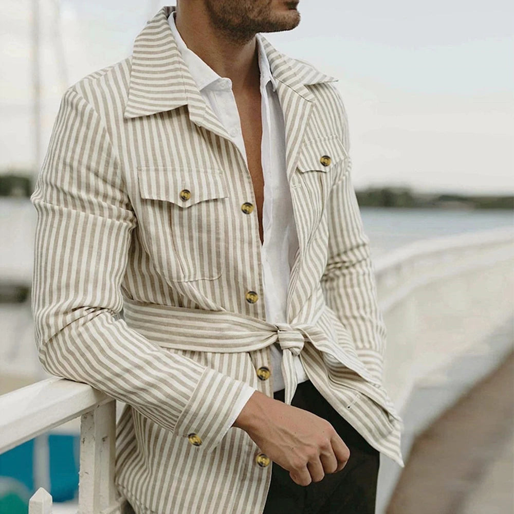 A man is standing, wearing a beige and white striped chore field safari blazer jacket with belt.