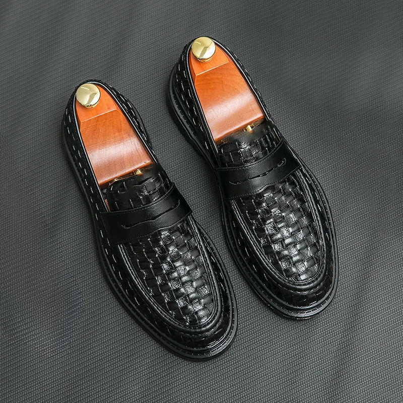 A pair of black men's woven loafers with black soles and shoe trees inside.