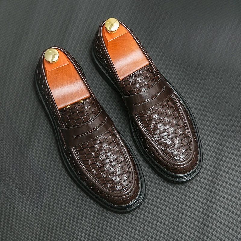 A pair of brown men's woven loafers with black soles and shoe trees inside.